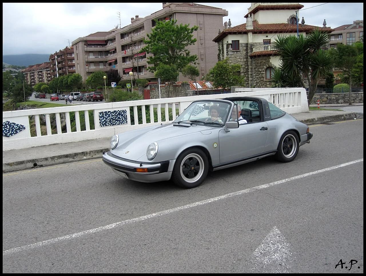 Silver 1977 Porsche 911 Targa driving on a city road